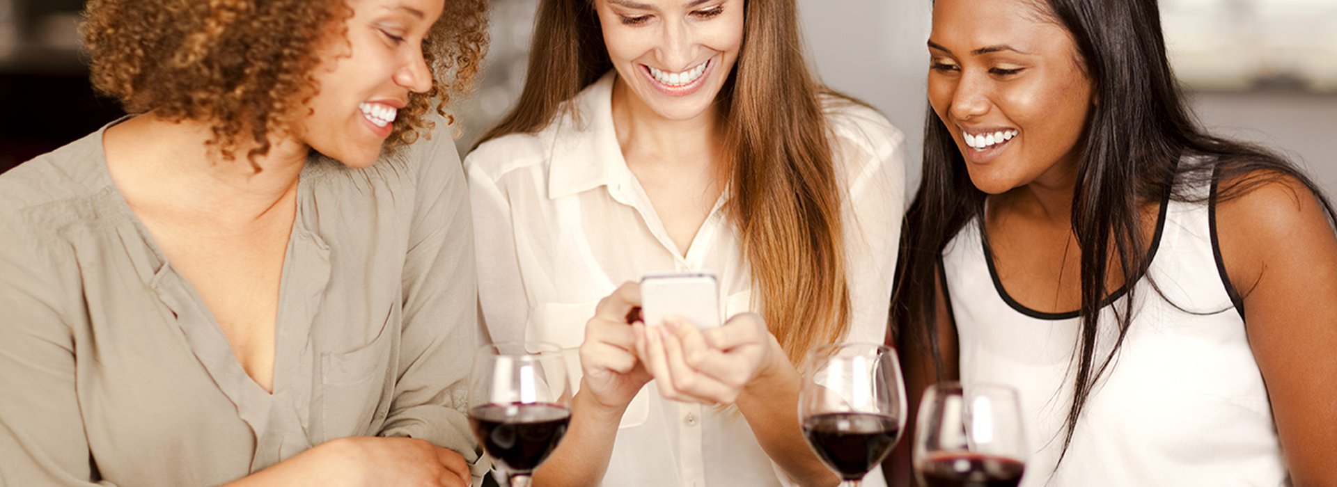 Group of mixed-race girls looking at a smartphone in a restaurant.